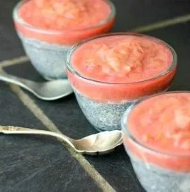 Homemade beautiful rhubarb sauce in a jar with fresh rhubarb stalks.