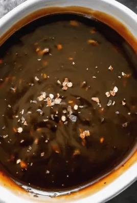 Homemade teriyaki sauce in a jar with ingredients on a wooden table