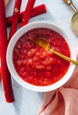Bowl of easy homemade rhubarb sauce with fresh rhubarb on the side.