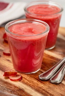Homemade easy rhubarb sauce in a glass jar with fresh rhubarb stalks