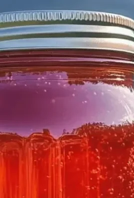 Homemade rhubarb syrup in a glass jar with fresh rhubarb stalks.
