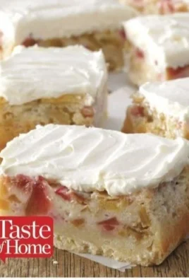 Rhubarb custard bars topped with cream and fresh rhubarb slices.
