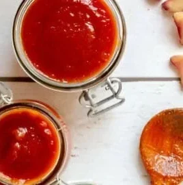 Homemade rhubarb sauce in a bowl with fresh rhubarb stalks