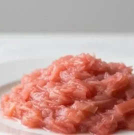 Homemade rhubarb sauce in a glass jar with fresh rhubarb stalks