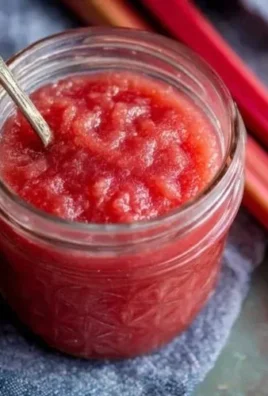 Delicious homemade rhubarb sauce in a glass jar with fresh rhubarb stalks