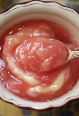 Homemade rhubarb sauce in a jar with fresh rhubarb stalks on the side.