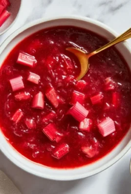 Homemade rhubarb sauce served in a bowl with fresh rhubarb stalks.