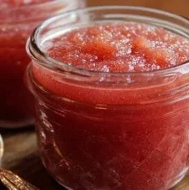 Delicious sweet and tart rhubarb sauce served in a bowl with fresh rhubarb stalks.