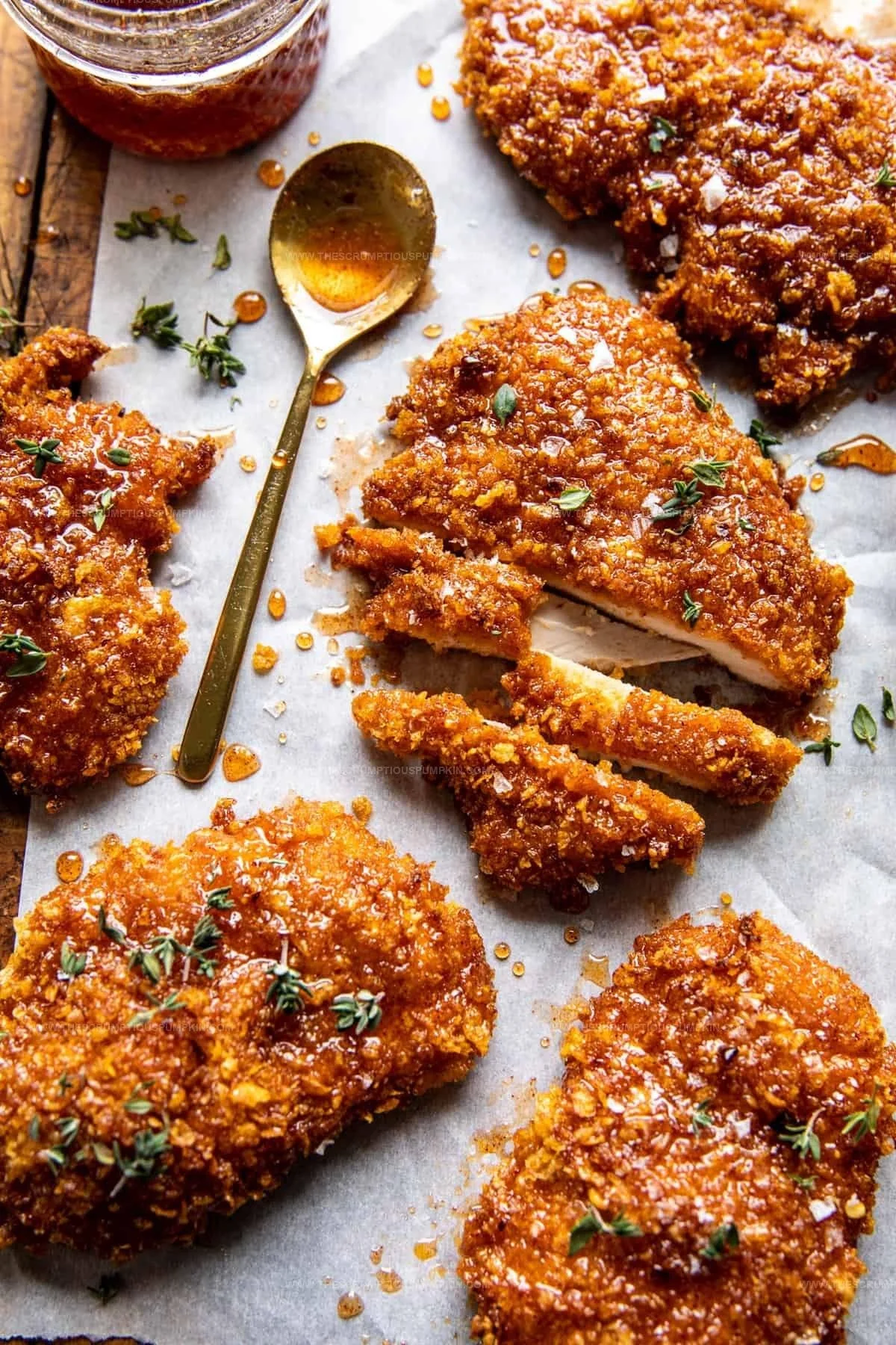 Baked crunchy hot honey chicken garnished with herbs and served on a plate.