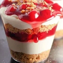 Delicious cherry cheesecake cups served in clear dessert cups with cherries on top.