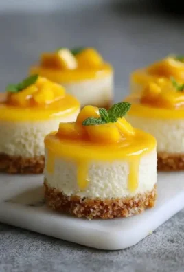 Mini mango cheesecakes served in dessert cups with fresh mango garnish