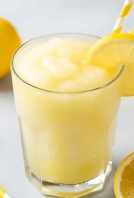 A refreshing glass of frozen lemonade with ice and a lemon slice on top.
