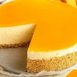 Delicious mango cheesecake served on a white plate with fresh mango slices.
