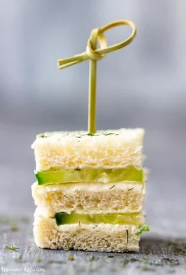 Plate of mini cucumber sandwiches with cream cheese and herbs