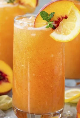A refreshing glass of peach lemonade garnished with fresh peaches and mint.