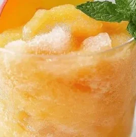 Refreshing Peach Lemonade Slush in a glass with peaches and lemon slices
