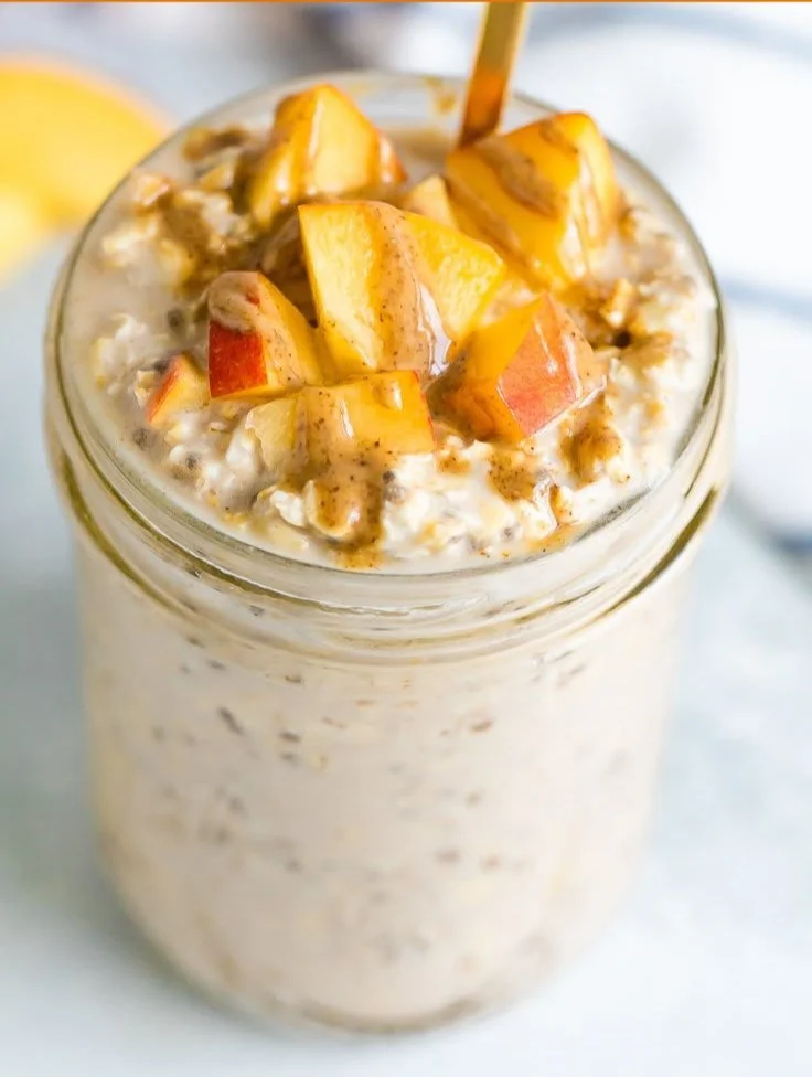 Delicious bowl of Peach Overnight Oats topped with fresh peaches and nuts