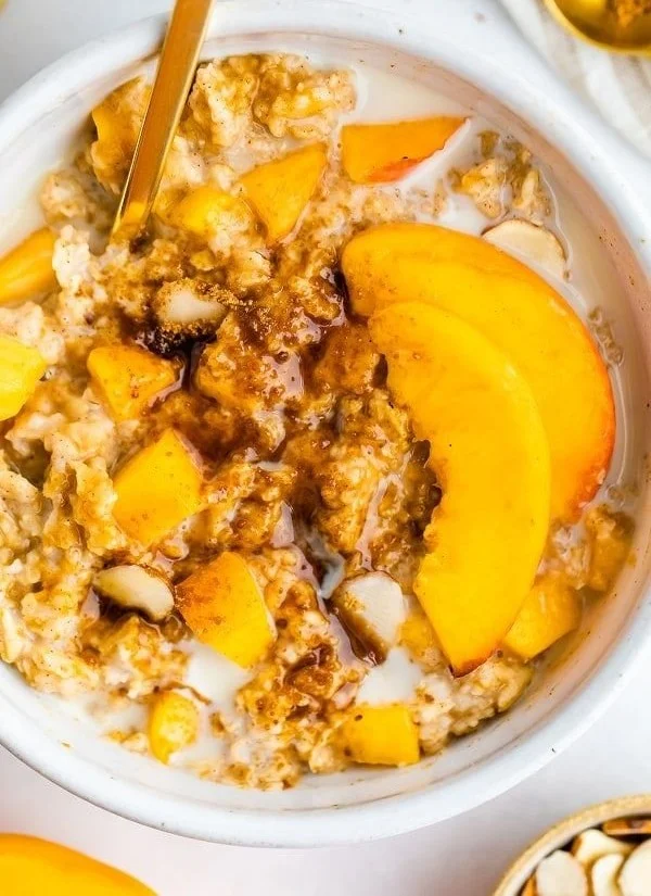 Bowl of Peaches and Cream Oatmeal topped with fresh peach slices and cream