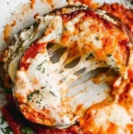 Healthy baked eggplant parmesan dish topped with fresh basil.