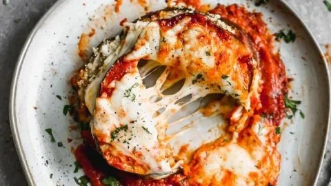 Healthy baked eggplant parmesan dish topped with fresh basil.