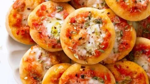 Colorful mini pizzas with various toppings on a baking sheet