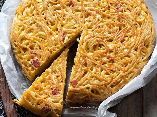 Delicious spaghetti frittata garnished with herbs on a rustic plate