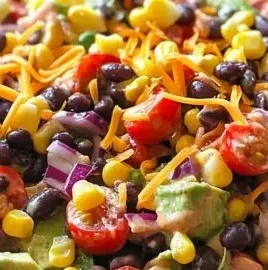 A vibrant cowboy salad with fresh vegetables, beans, and dressing in a bowl.