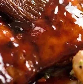 Delicious sticky grilled chicken served on a plate, showcasing its glaze and grill marks.