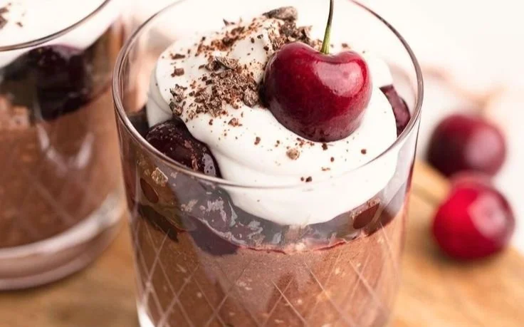 Bowl of chocolate cherry overnight oats topped with fresh cherries and chocolate chips.