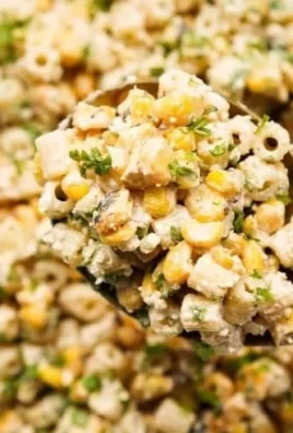 Creamy elote pasta salad with corn and zesty dressing in a bowl.