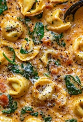 A bowl of creamy spinach tomato tortellini garnished with fresh basil.