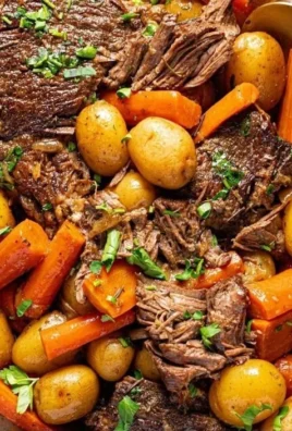 Delicious crock pot pot roast served with vegetables and herbs.
