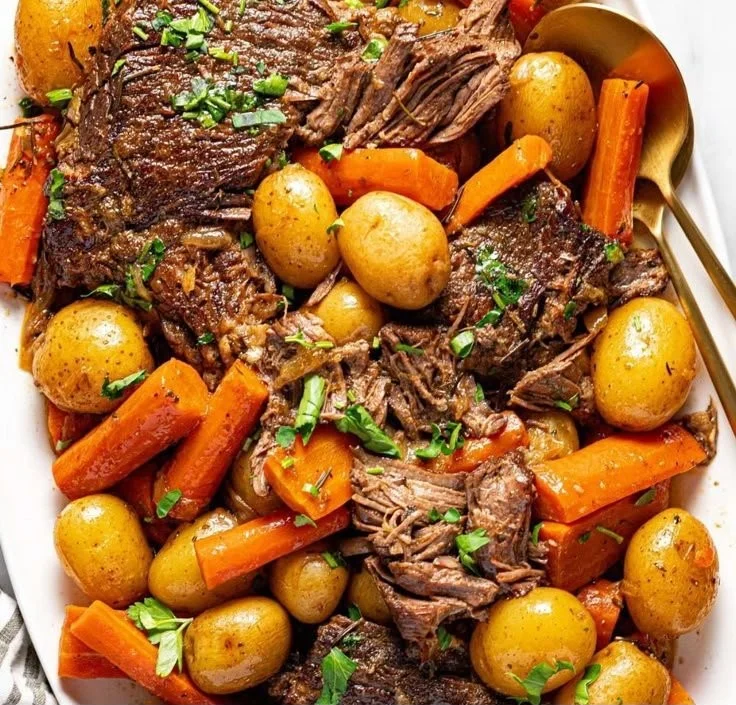 Delicious crock pot pot roast served with vegetables and herbs.