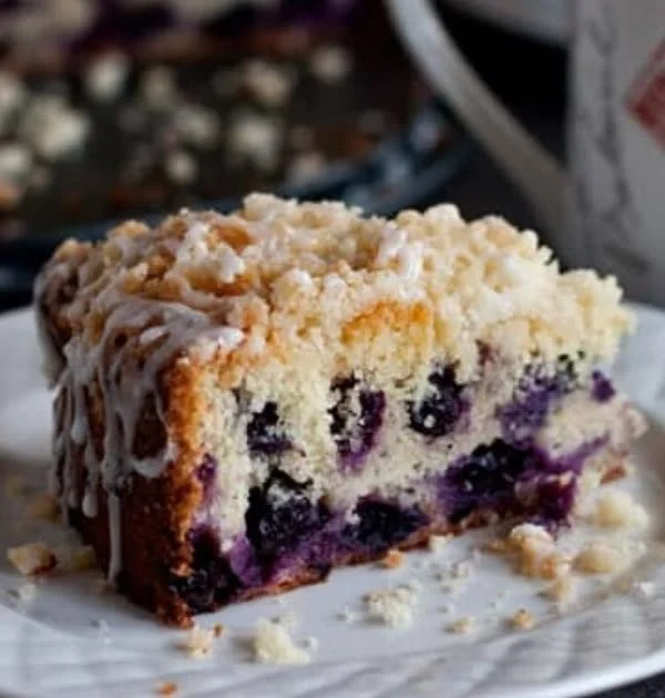 A delicious slice of Lemon Blueberry Coffee Cake on a plate, garnished with blueberries.