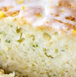 Sliced lemon zucchini bread on a wooden board with lemon zest