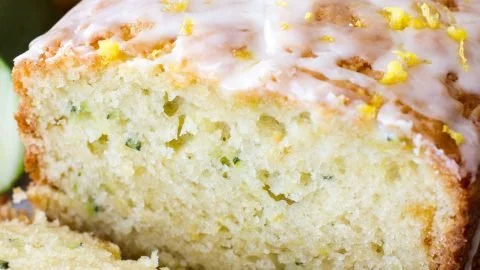 Sliced lemon zucchini bread on a wooden board with lemon zest