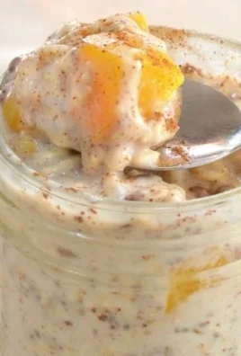 Bowl of Overnight Peach Cobbler Oatmeal topped with fresh peaches and cinnamon