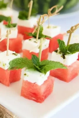 Watermelon feta skewers with mint garnish on a white plate