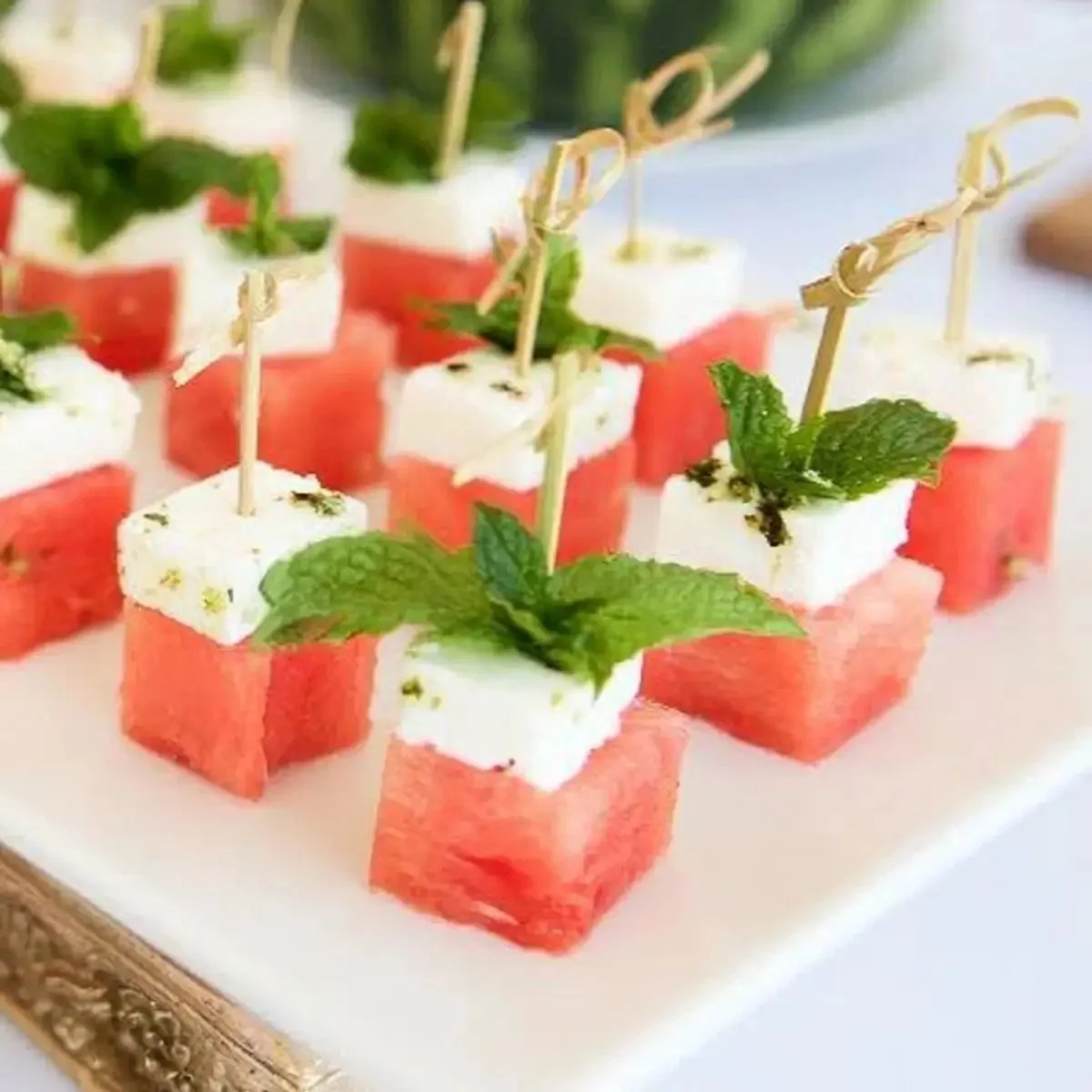 Watermelon feta skewers with mint garnish on a white plate